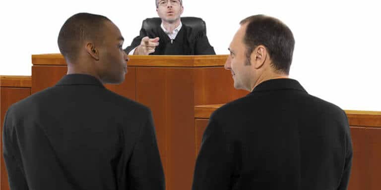 Judge motioning to two men standing in front of him in a court scenario