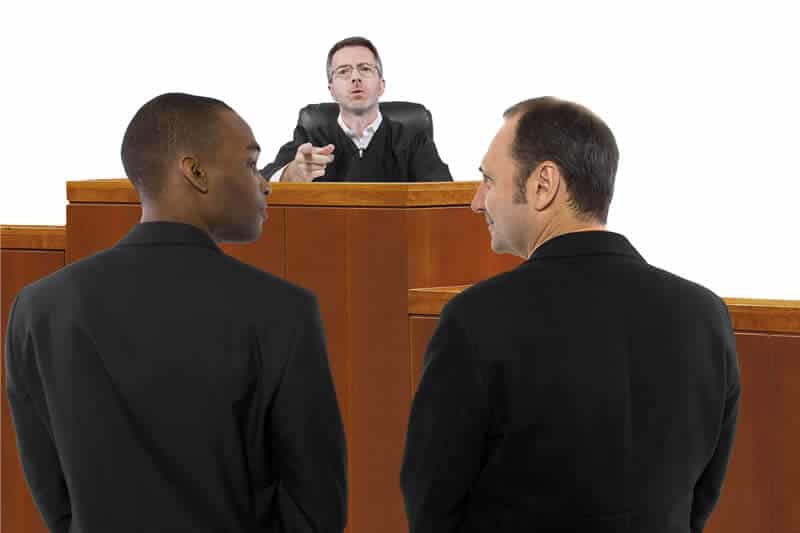 Judge motioning to two men standing in front of him in a court scenario
